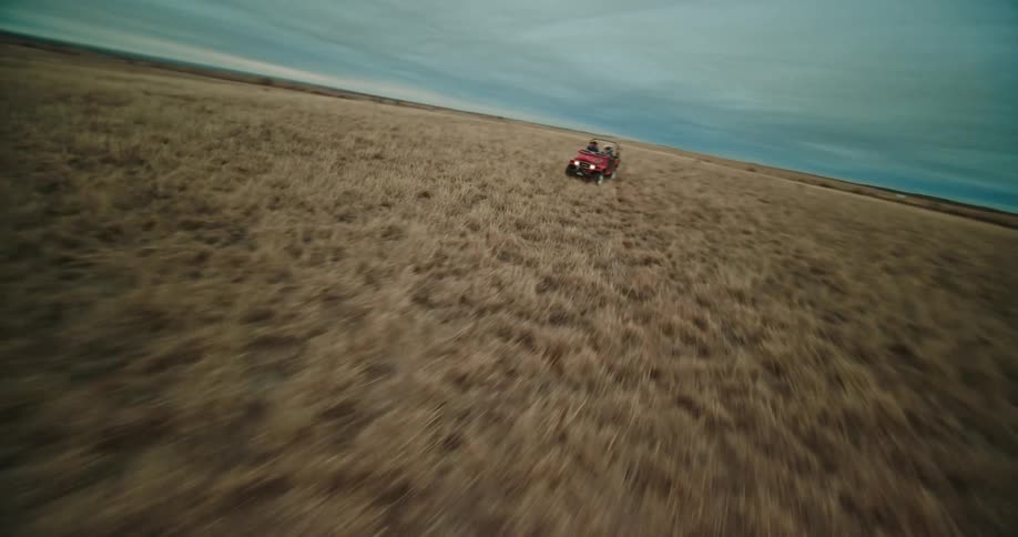 Aerial view of red jeep driving in the field