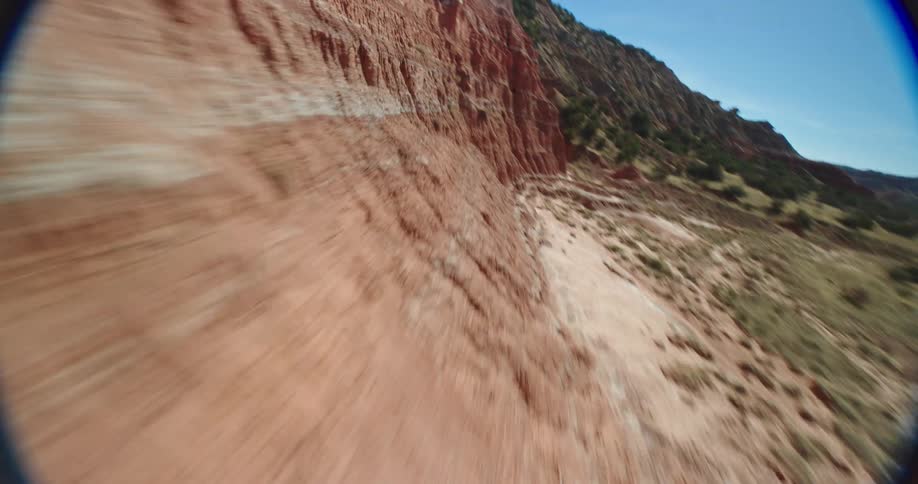A camera mounted on a high speed drone flies over a rock formation