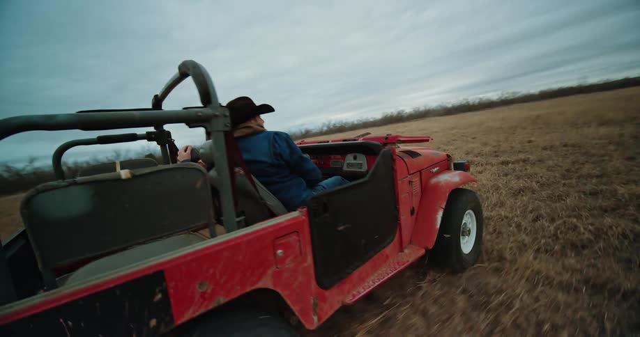 Aerial view of man and woman driving red landcruiser in the field