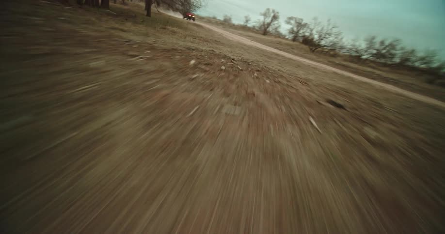 A drone view going through a forest revealing a red jeep driven on a dirt road