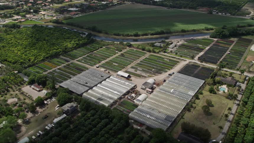 Aerial footage of farmland and greenhouses in South Miami Heights FL during a sunny day