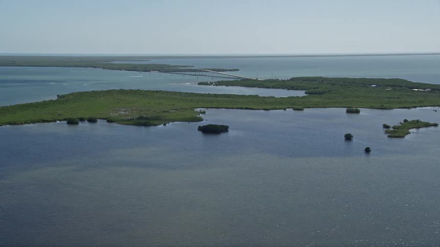 Aerial view flying over a lagoon with Card Sound Bridge visible in the distance Homestead Florida on a sunny day