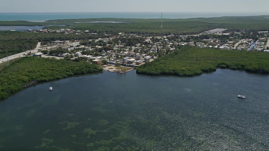 Aerial view of Lake Surprise Key Largo Florida as the camera approaches a residential neighborhood near the sea and bridge during daytime hours