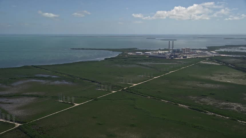 Aerial view flying over power lines reveals Turkey Point Power Plant in Homestead FL on a sunny day