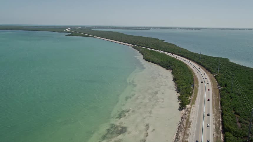 A car tracking aerial view of light traffic approaching and driving on Overseas Highway in Key Largo Florida