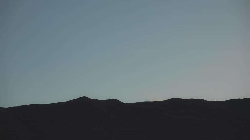 Mountain being silhouetted agains the blue sky at dusk