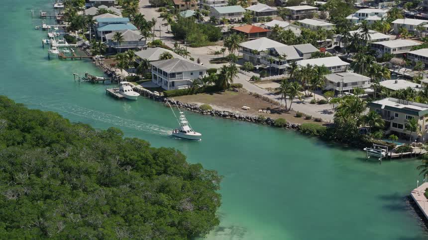 Aerial view of a fishing boat orbiting along Tavernier Creek in Florida surrounded by residential buildings and beautiful scenery