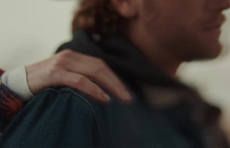 A woman rubs the back of a man who is wearing a cowboy hat