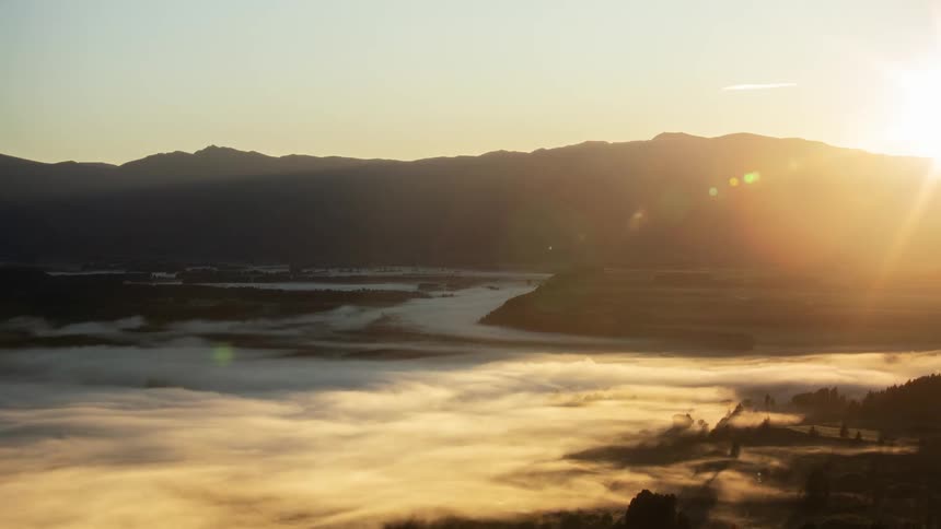 A time lapse of low fog running across a field as the sun rises