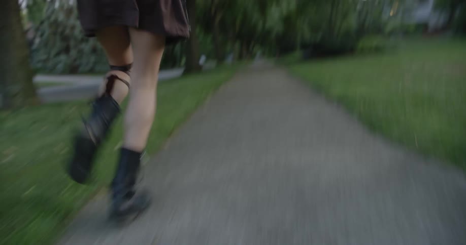 Woman with a pair of boots brown skirt and cloak runs on the sidewalk in the street