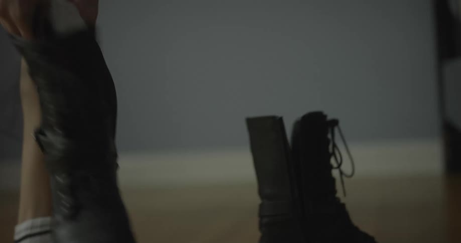 A young girl puts on a boot and grabs another one