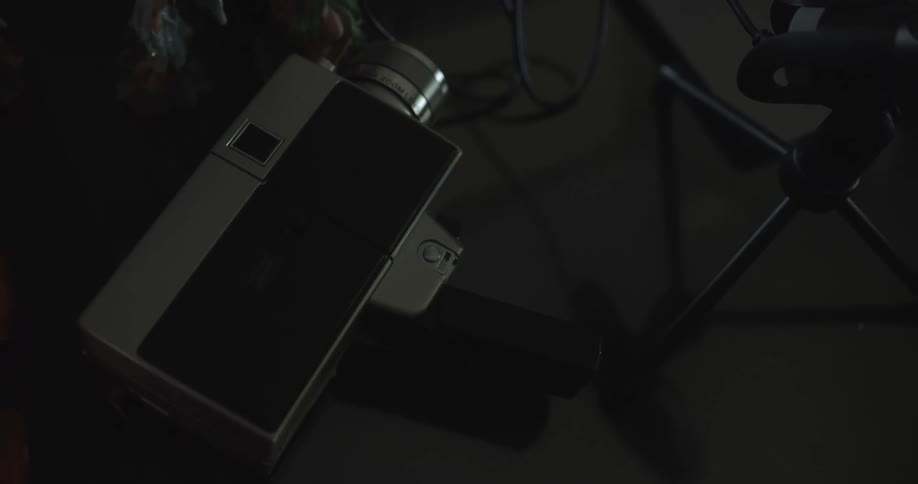 An older style of handheld video camera lays on its side on the floor