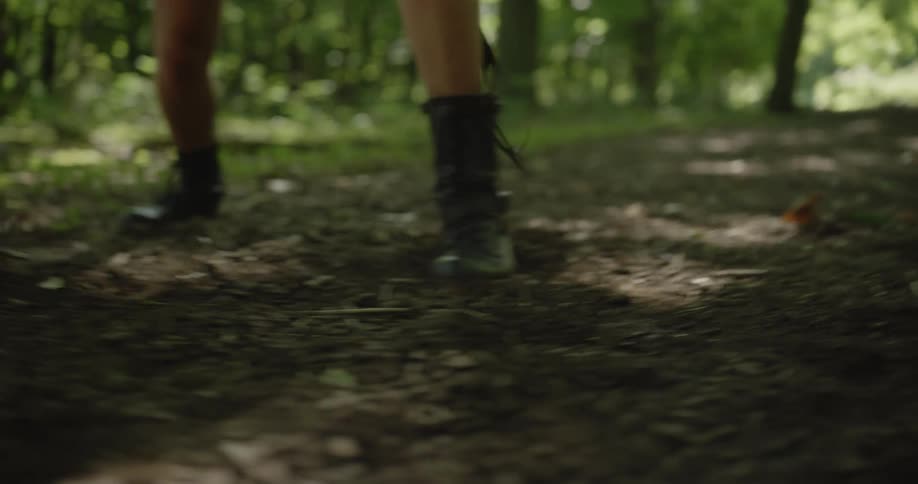 Woman with a pair of boots practices fighting in the green woods