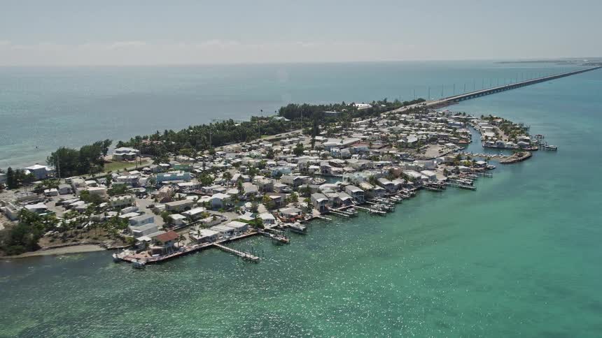 Approaching and flying by a coastal Florida neighborhood with houses all along the water