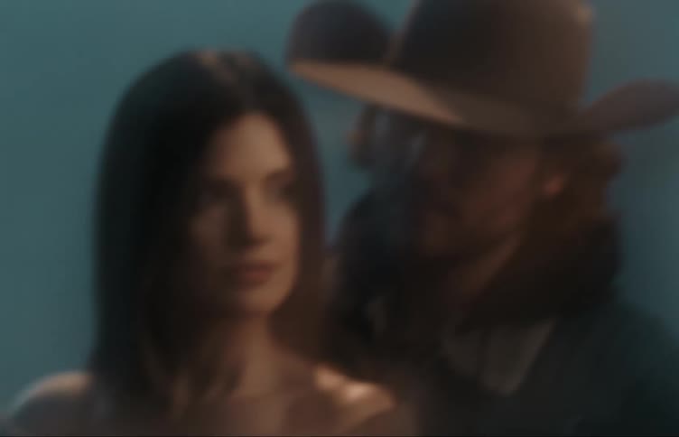 A man wearing a cowboy hat standing behind a women looking at her as she looks forward