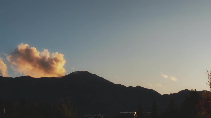 A time lapse of clouds going over a mountain at dusk