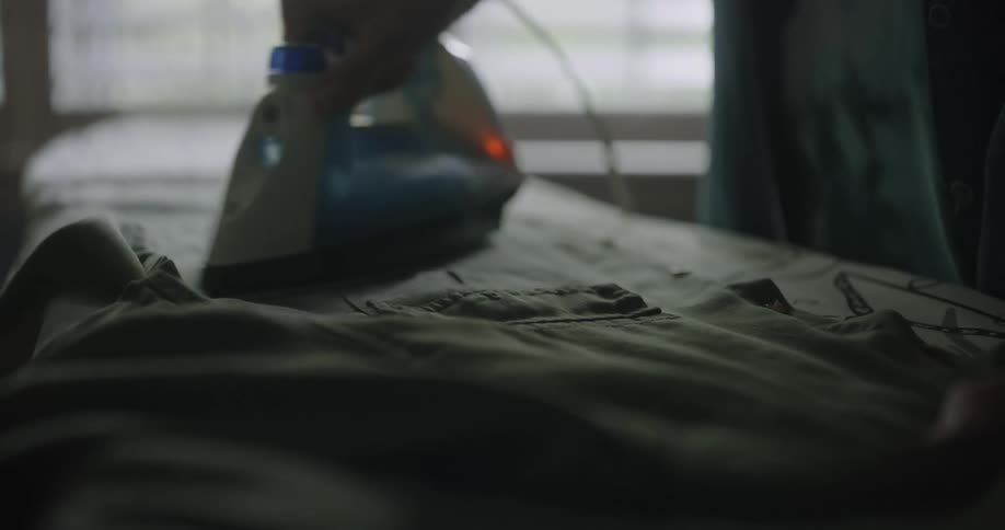 A person irons a shirt on an ironing board