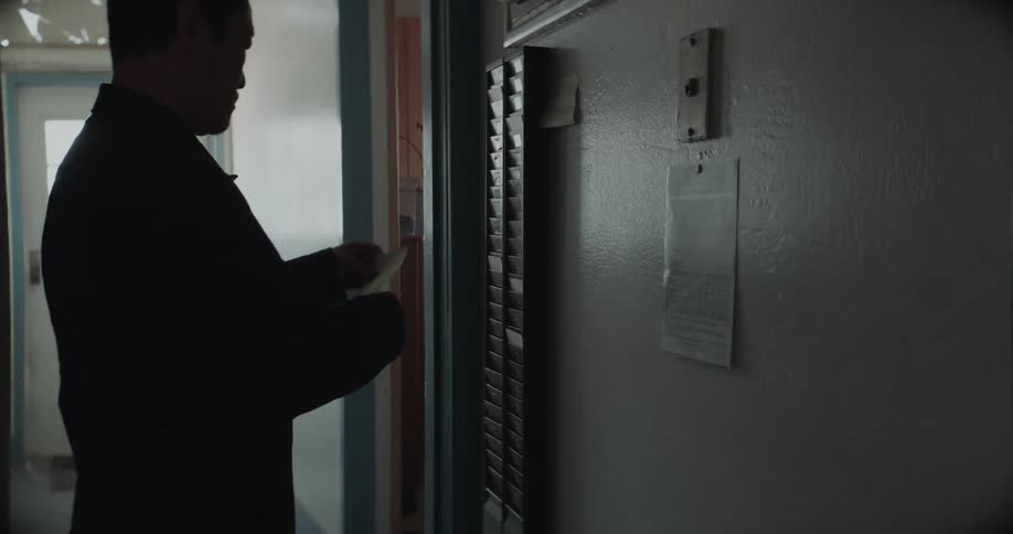 Asian man runs his time card through the punch clock and then heads to the door