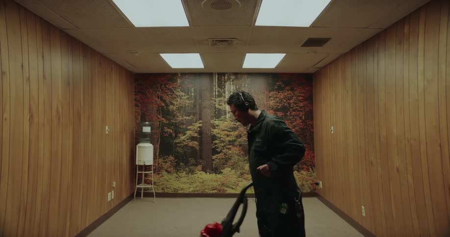 A man is vacuuming an empty room by himself