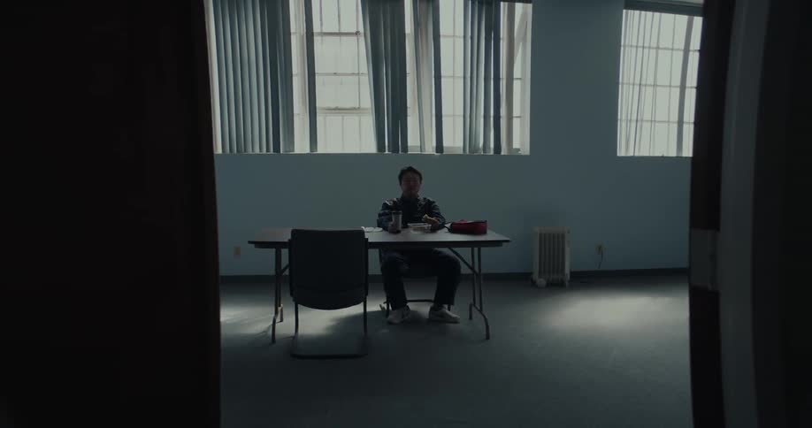 A man sitting at the table in lunch room eating pizza and drinking coffee