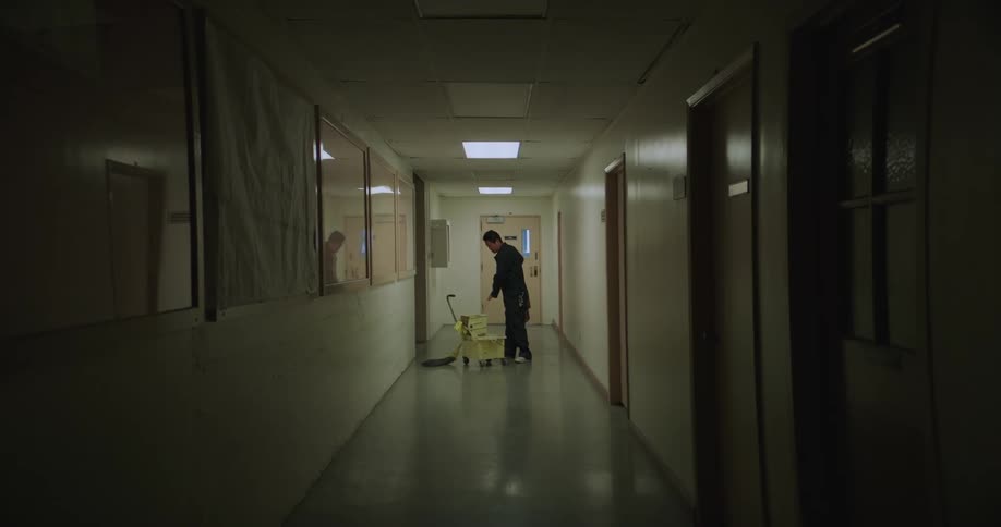 Male cleaner mops up corridor in the building