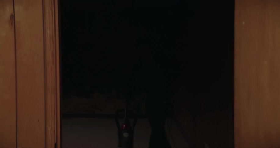 Man vacuums in a room with a flickering light while wearing headphones as seen through vignette