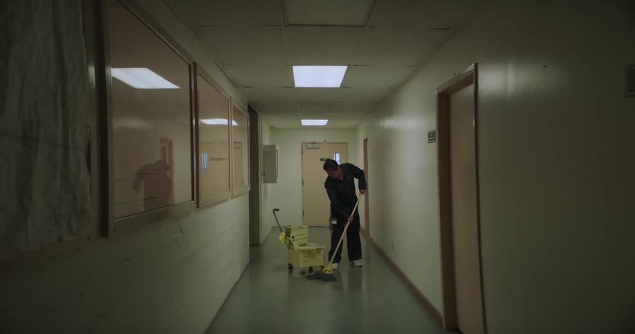 Janitor mops the floor in a hallway as seen through a fisheye lens