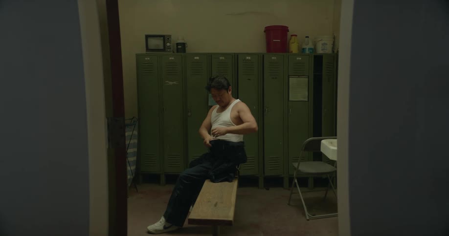 A man is getting dressed in the locker room