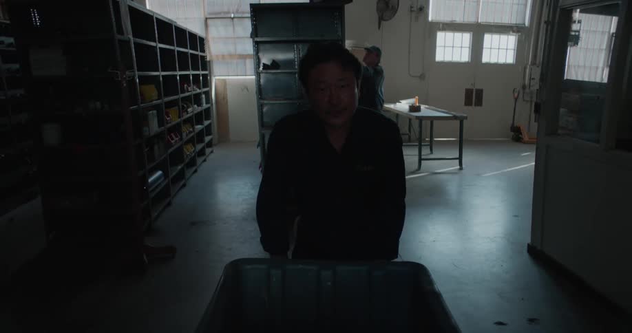 A man is carrying a trash bin in a work area