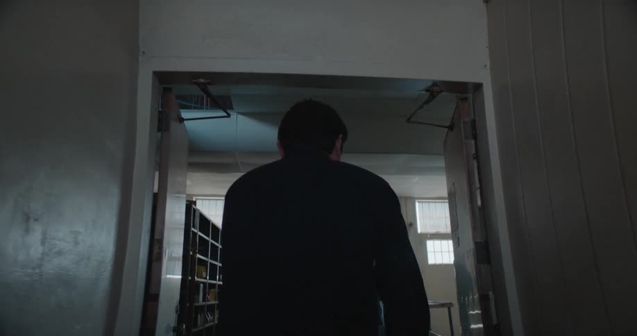 A man is pushing a container through hallways and past shelves in a facility