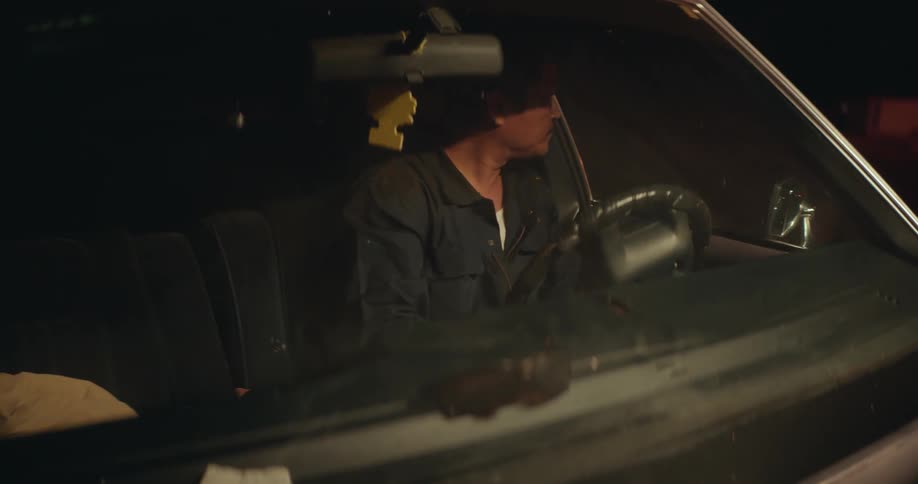 Man drives a car and turns a steering wheel at night