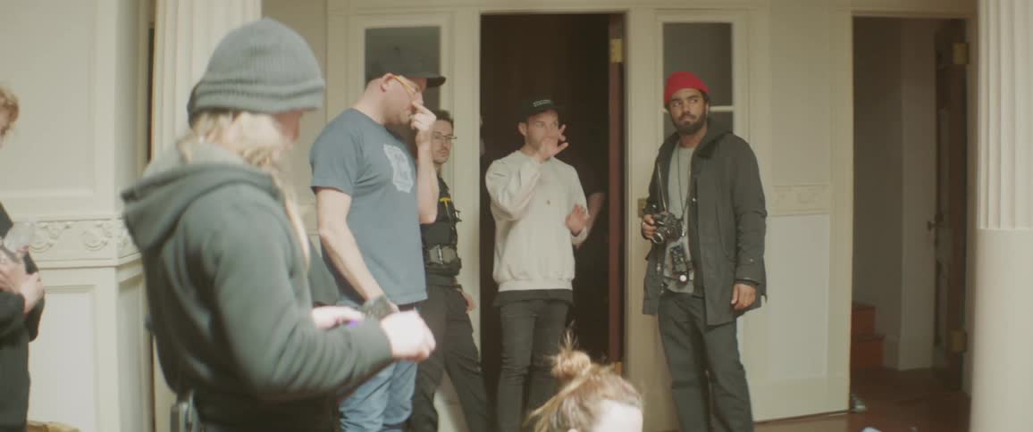 A group of people stand together in the room talking