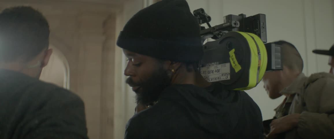 A man is filming others in the hallway