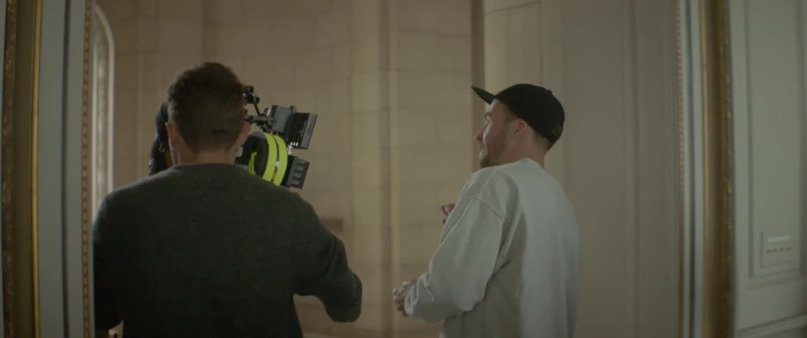 Camera crew walks in a hallway and up stairs