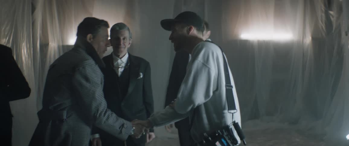 Two men shake hands as other men stand nearby