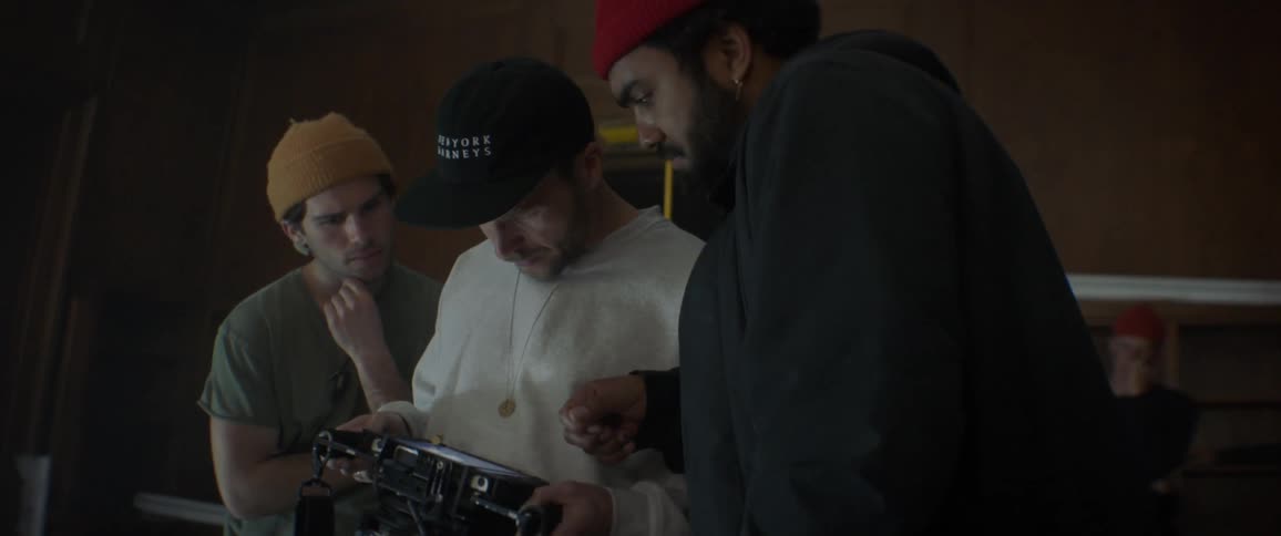 Three people look at camera footage together and talk