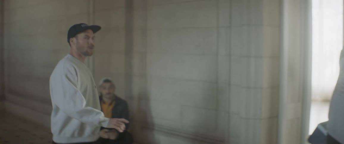 A man gives direction and gestures in a building hallway