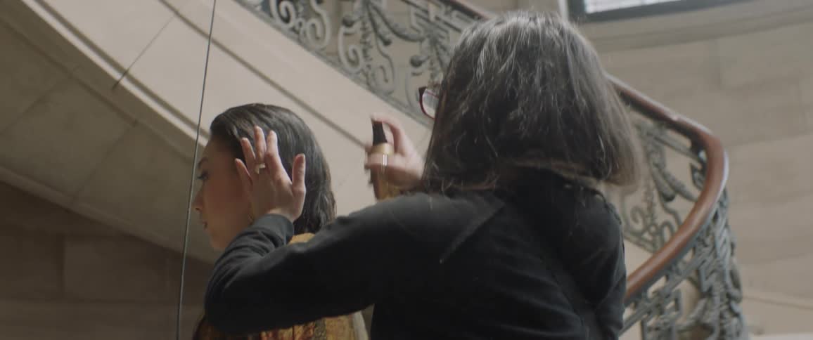 A woman is spraying the hair of another