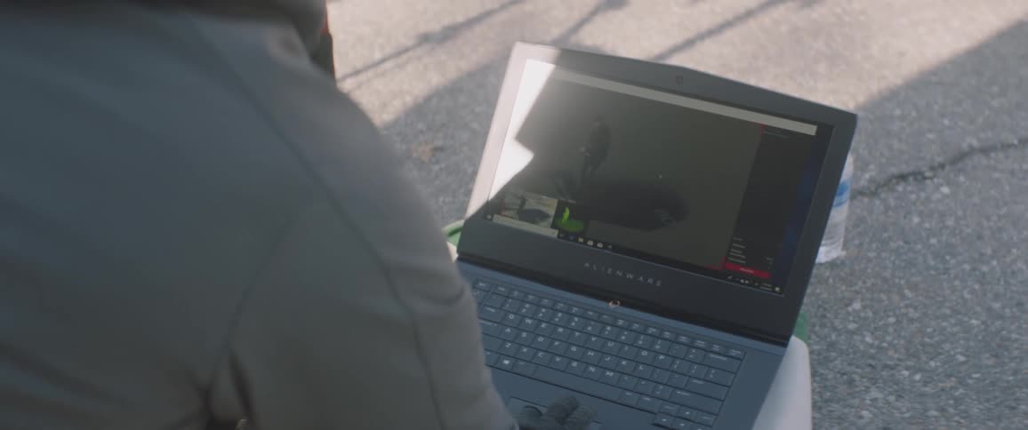 A person watches video on a laptop on a sunny day