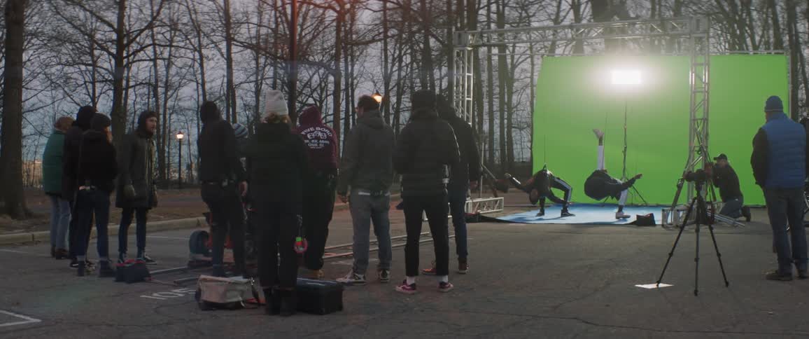 Man pushes a video camera as other men watch