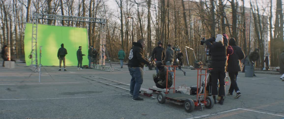 A film crew is preparing a green screen scene outdoors