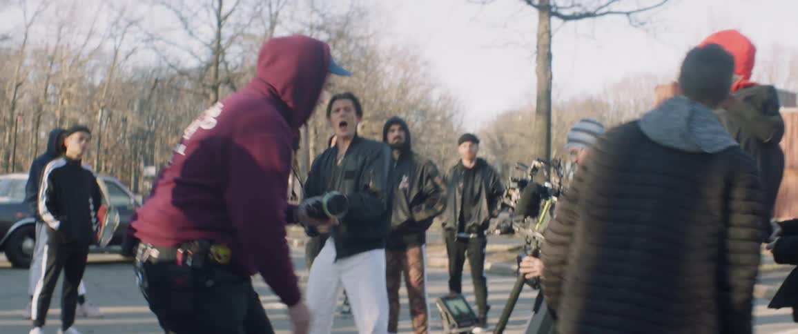 Film crew records outside in a parking lot surrounded by trees