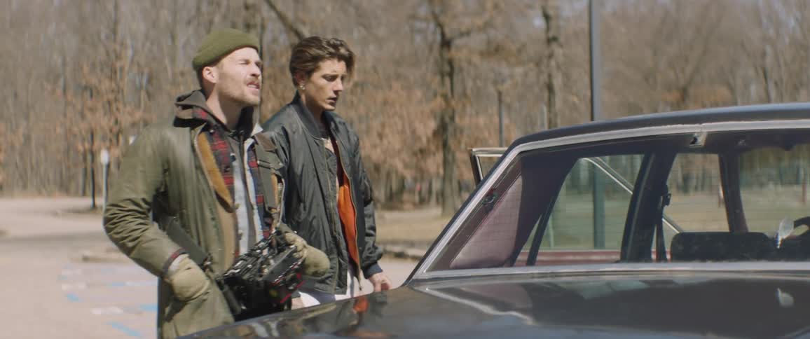 A man wearing a camera gives direction to an actor on an outdoor set