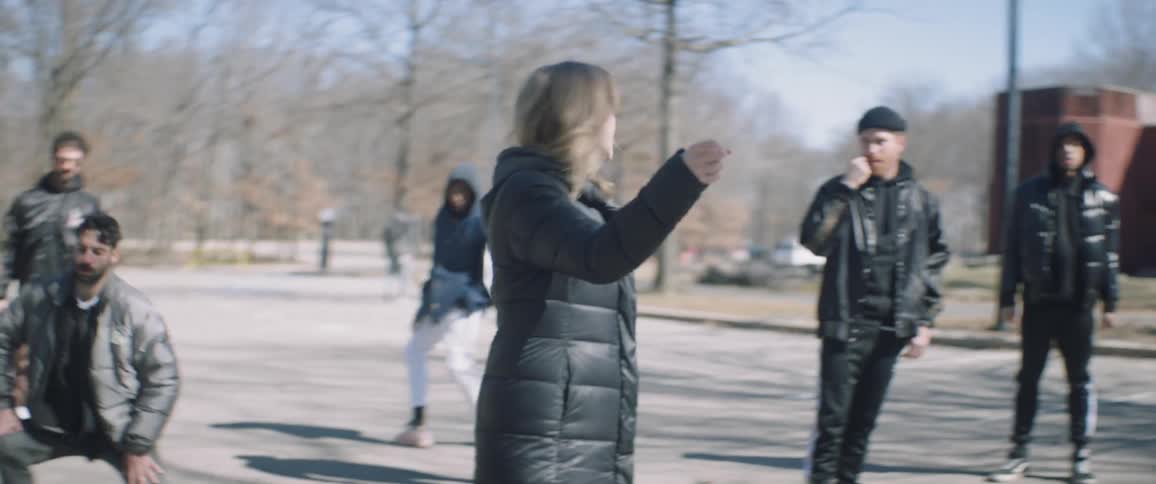 A woman choreographs and directs dance moves on an outdoor set