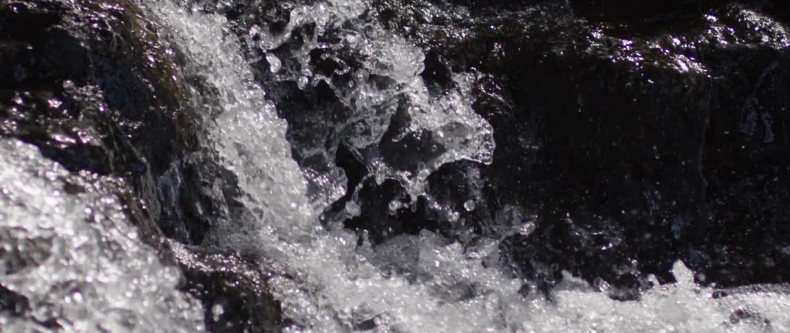 A waterfall plunges over dark rocks