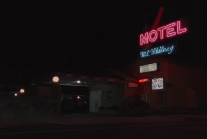 A motel with a neon sign lit up at night