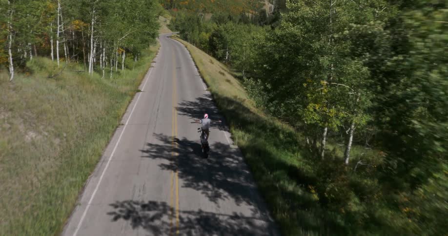A motorcyclists performs a stunt by standing on his moving bike