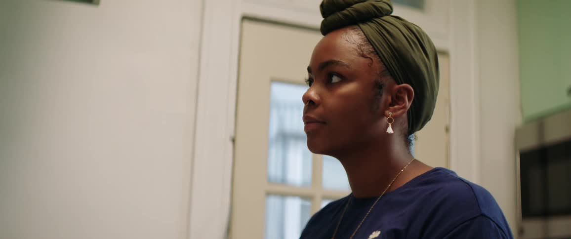 Black woman with a dark green headband does the dishes in the kitchen