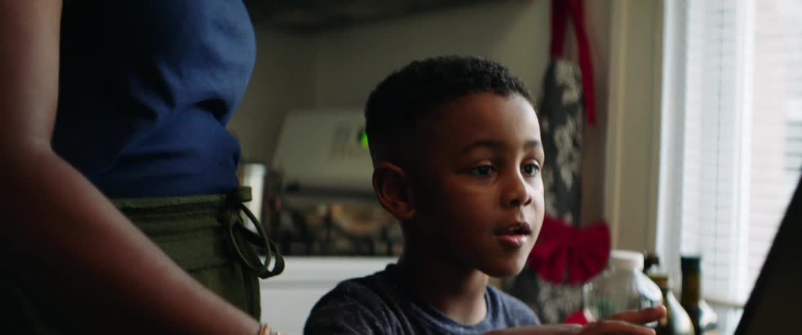 A mother helps her son use the laptop