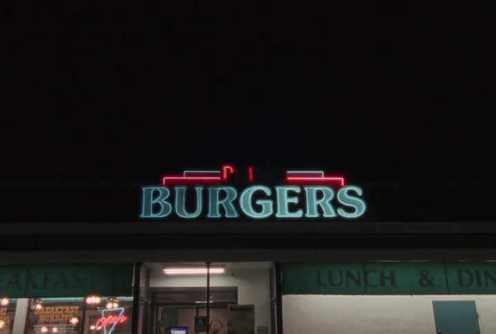 A neon sign that says burgers lit up at night on a restaurant